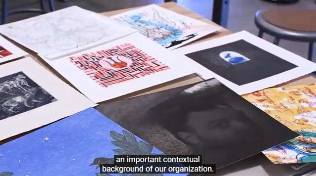 Screenshot of the Zuckerman Archives. Several prints on a table being sorted