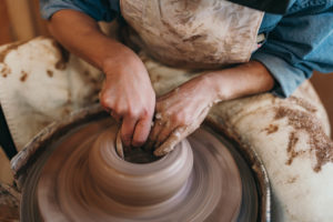 A person making a clay bowl or vase on a wheel